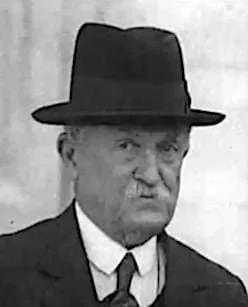 Black and white photo of a man in a suit and hat

Automatically generated description